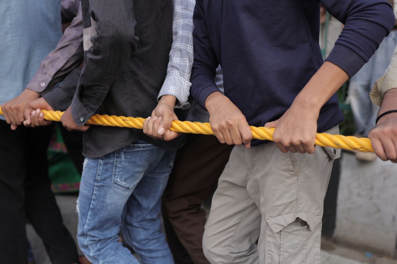 Close-up of a group participating in a tug of war, emphasizing teamwork and strength.